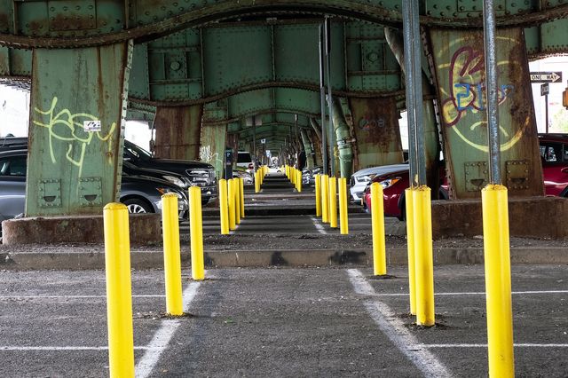 yellow parking pylons under an elevated highway